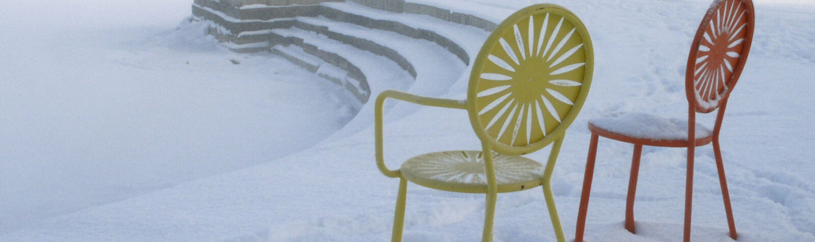 Iconic union chairs covered in snow along the shore of Lake Mendota.